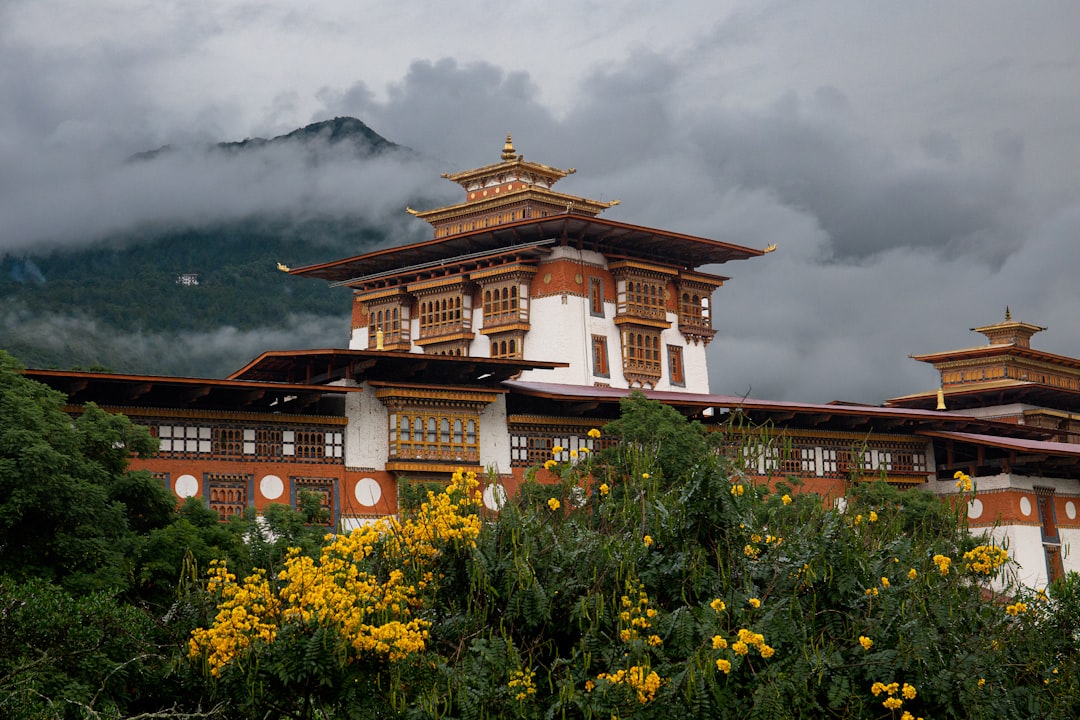 A Bhutanese dzong framed by cloud and flowering shrubs