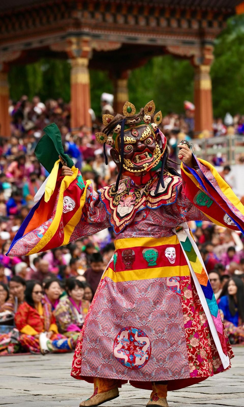 A masked dancer performing before the crowd at a Bhutanese tshechu